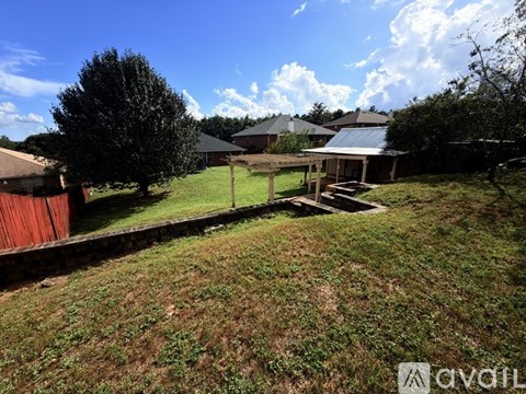 A grassy yard with a house and a tree in the background.