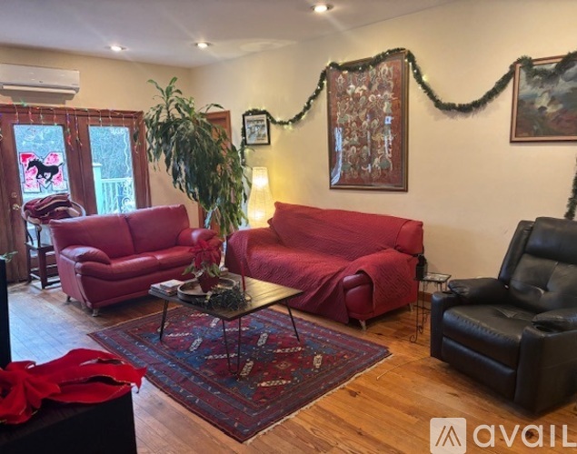 A living room with a red couch and a coffee table with a vase of flowers on it.