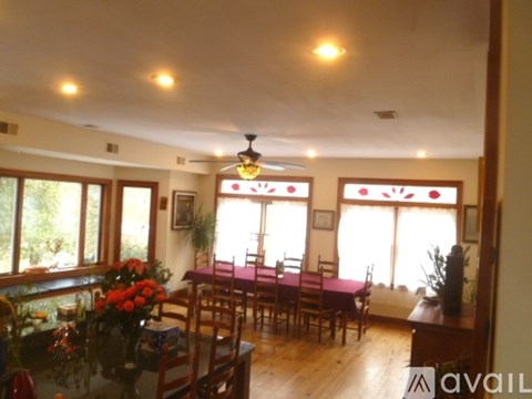 A dining room with a table set for six and a ceiling fan.