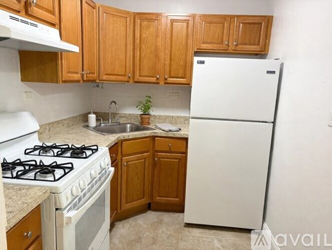 A kitchen with a white fridge, white stove and wooden cabinets.