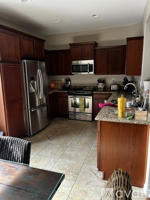 A kitchen with a refrigerator, microwave, oven, and sink.
