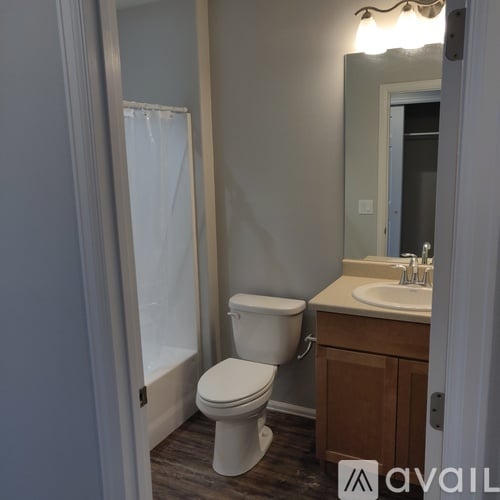 A white toilet is in a bathroom with a mirror and sink.
