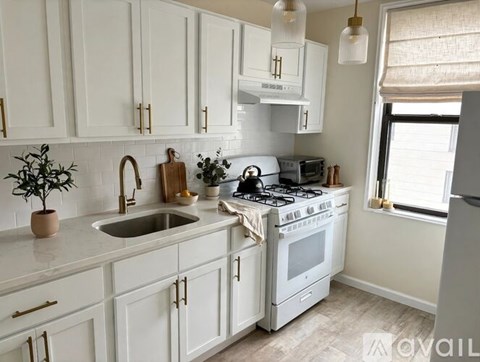 A kitchen with white cabinets and a white stove top oven.