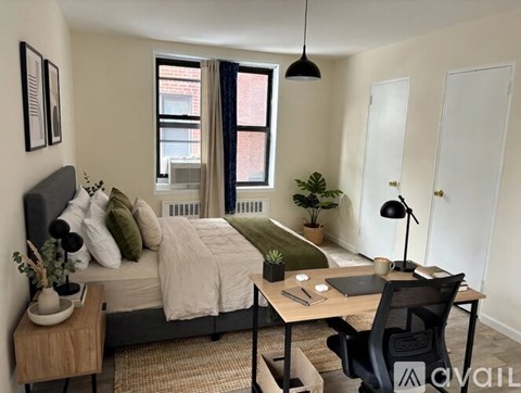 A bedroom with a bed, desk, chair, and a window with a view of a building outside.