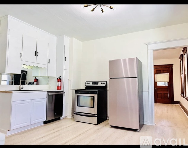 A kitchen with a stainless steel refrigerator, a black oven, and a white cabinet.