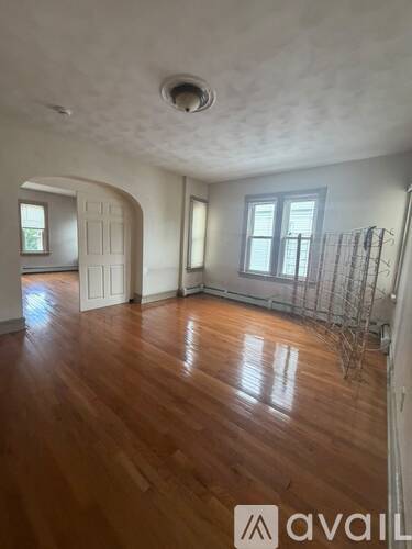 A room with wooden floors and a window with bars on it.