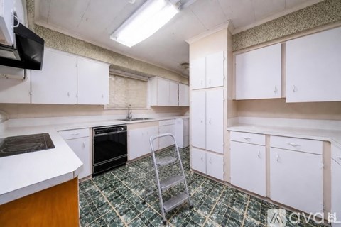 A kitchen with white cabinets and a green tile floor.