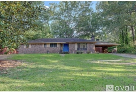 A house with a blue door is surrounded by trees.