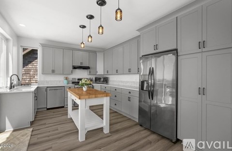 A modern kitchen with a wooden table and stainless steel appliances.