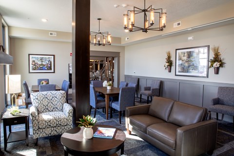 A living room with a brown leather couch and a patterned chair.
