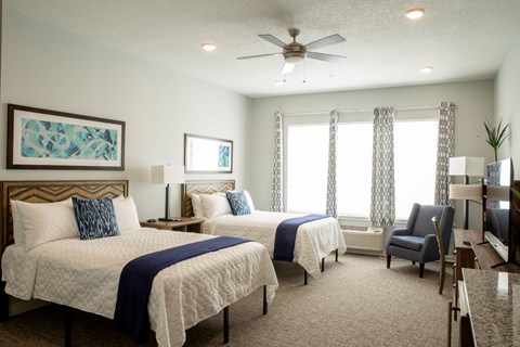A bedroom with two beds and a ceiling fan.