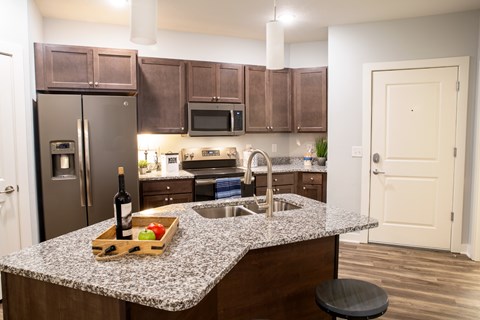 A kitchen with a granite counter top and a wine bottle on it.