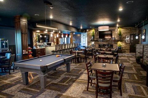 A pool table is surrounded by chairs in a room.