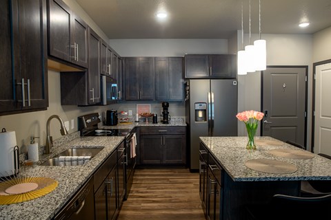 A kitchen with dark wood cabinets and granite countertops.