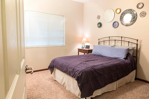 A bedroom with a bed, nightstand, and wall decorations.