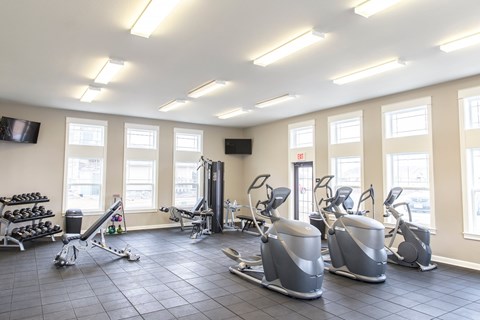 A gym with a variety of equipment including treadmills, weights, and exercise machines.