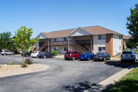 A sunny day at a residential area with cars parked in front of a building.