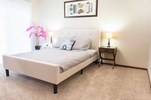 A bedroom with a large bed and a pink plant.