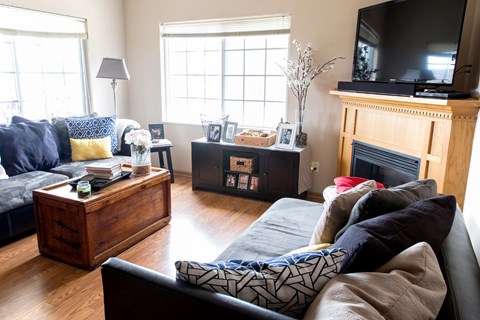 A living room with a black couch and a wooden coffee table.