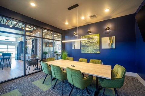 A conference room with a long table and green chairs.