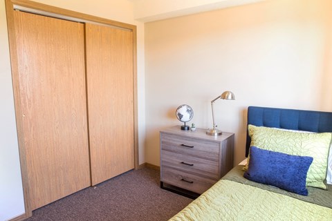A bedroom with a bed, nightstand, and wardrobe.