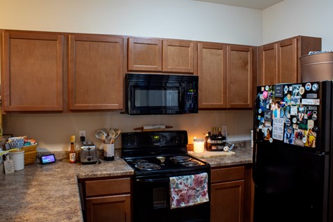 A kitchen with wooden cabinets and a black fridge covered in magnets.