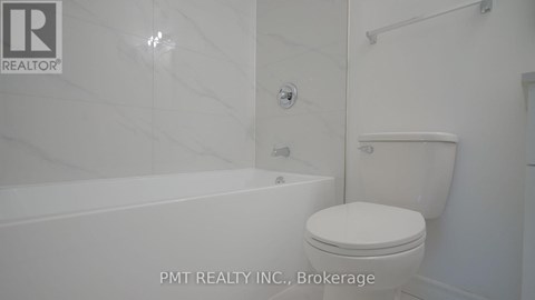 A white toilet in a bathroom with a marble wall.