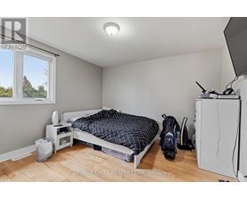 A bedroom with a bed, a microwave, a fridge, and a window.