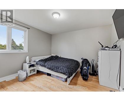 A bedroom with a bed, a microwave, a fridge, and a window.