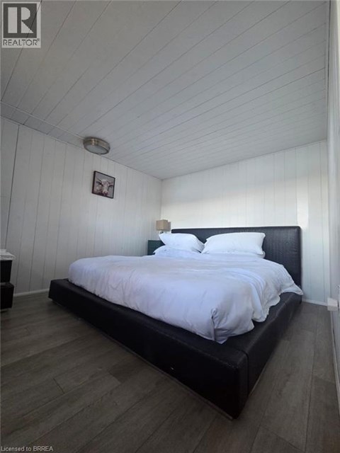 A bedroom with a black bed and a wooden floor.