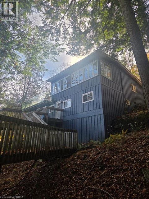 A house with a dark blue exterior is surrounded by trees.