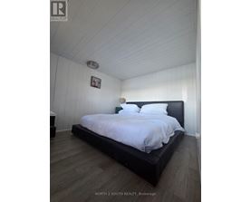 A bedroom with a bed, nightstand, and a picture on the wall.