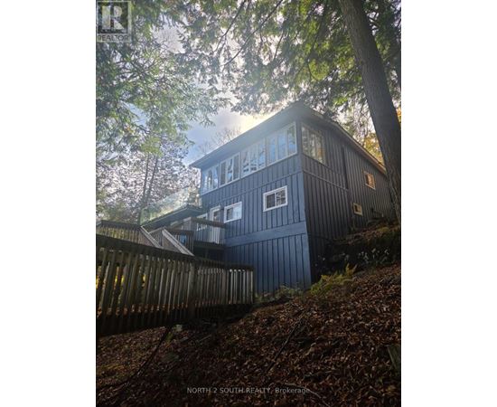 A house with a dark blue exterior is surrounded by trees.