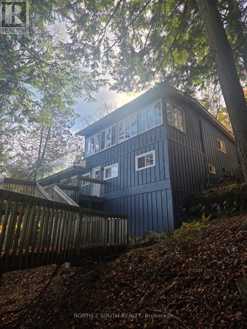 A house with a dark blue exterior is surrounded by trees.
