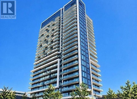 A tall building with many windows and balconies is under a clear blue sky.