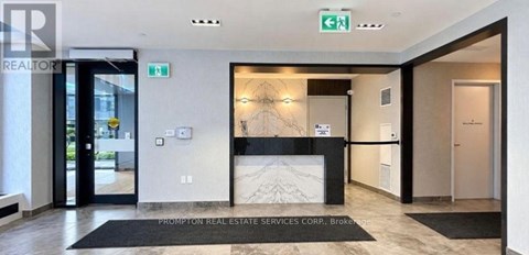 The image shows the front desk of Prompton Real Estate Services Corp. Broker with a black and white marble pattern on the wall behind it.