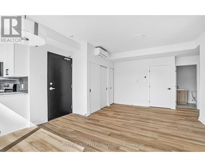 A spacious room with wooden flooring and white walls.