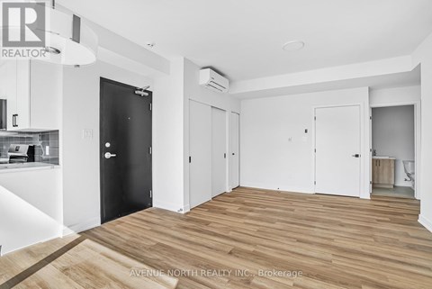 A spacious room with wooden flooring and white walls.