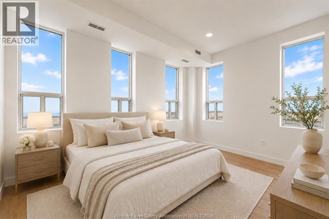 A bedroom with a large bed and a view of the sky through the windows.