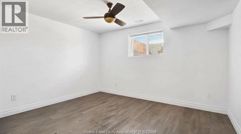A room with a ceiling fan and a window with blinds.