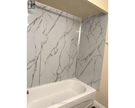 A white bathtub in a bathroom with marble wall tiles.