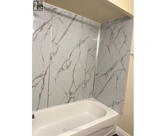 A white bathtub in a bathroom with marble wall tiles.