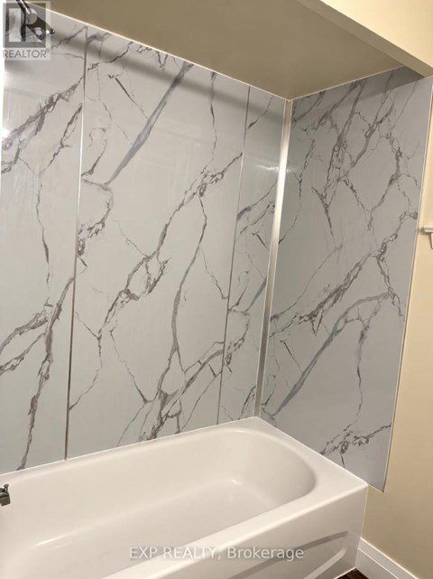 A white bathtub in a bathroom with marble wall tiles.