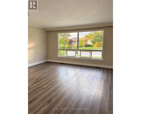A room with wooden flooring and a large window overlooking a street.