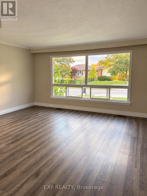A room with wooden flooring and a large window overlooking a street.