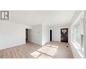 A spacious room with wooden flooring and white walls.