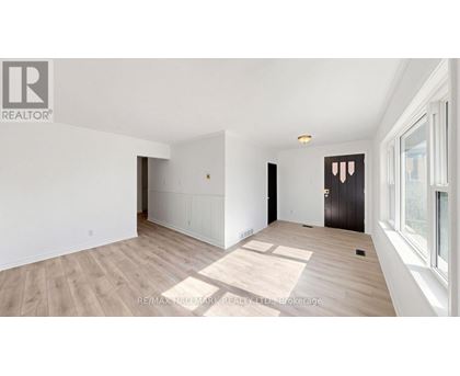 A spacious room with wooden flooring and white walls.