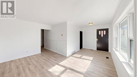 A spacious room with wooden flooring and white walls.
