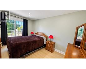 A bedroom with a bed, nightstands, and a window with a view of a fence and trees.