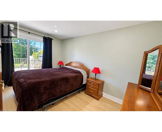 A bedroom with a bed, nightstands, and a window with a view of a fence and trees.